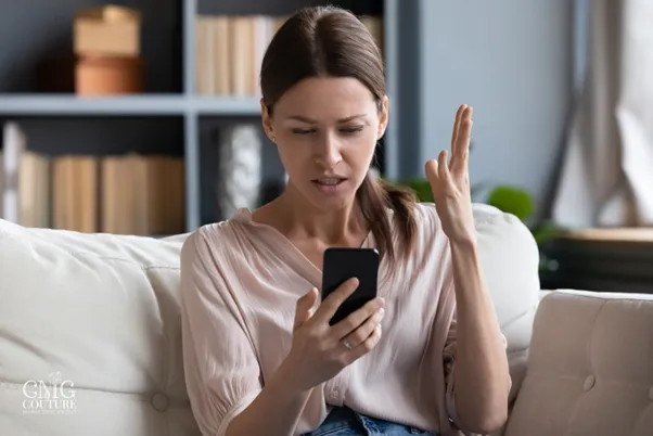 A woman holds her phone, intently looking at the screen, possibly engaging with digital content or social media